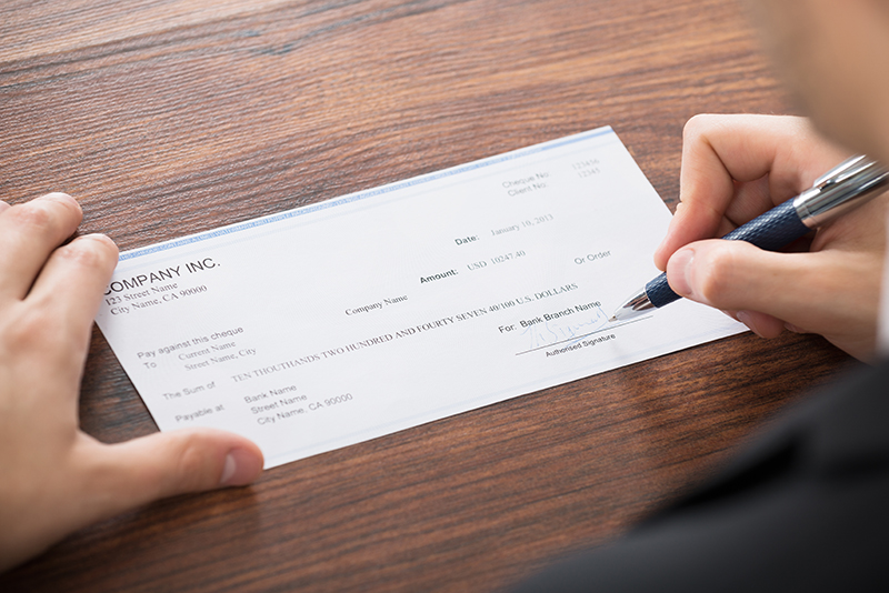 Close-up,Photo,Of,Businessman,Filling,Blank,Cheque